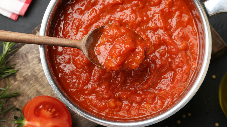 Cooking tomato sauce on the stove with a spoon