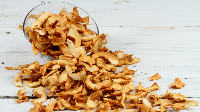 Apple chips with a bowl on wooden surface