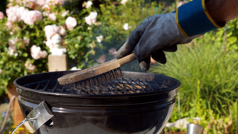 man cleaning grill with brush