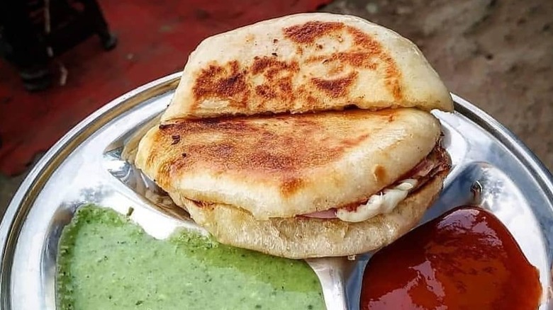 A kalari kulcha sandwich on a plate with chutney