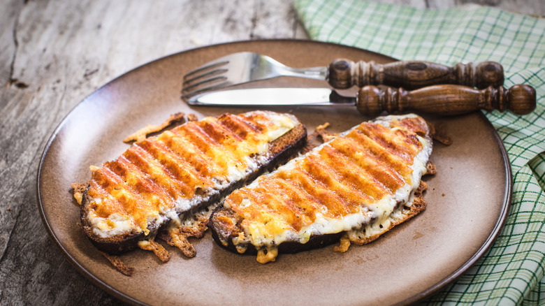 Two pieces of Welsh rarebit on a plate with mustard