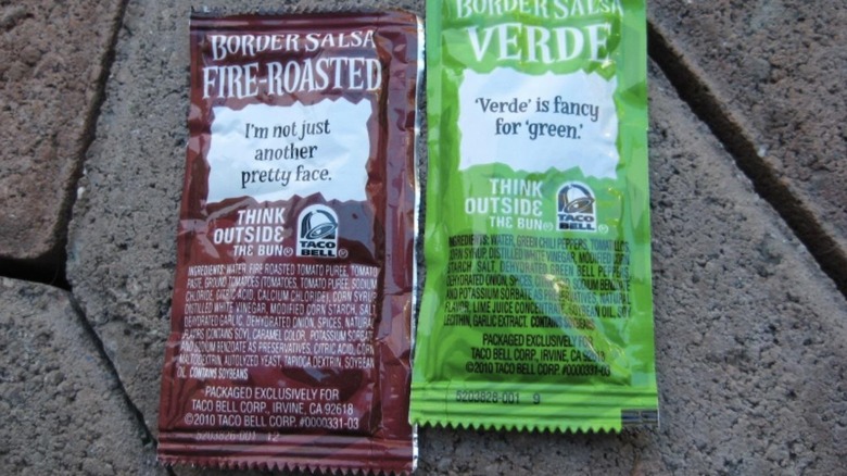 Sachets of Taco Bell Fire‑Roasted Sauce lying side by side on a sidewalk