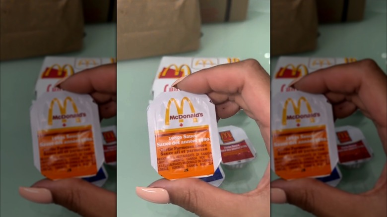 Someone's hand holding a packet of McDonald's Garlic Parmesan Sauce