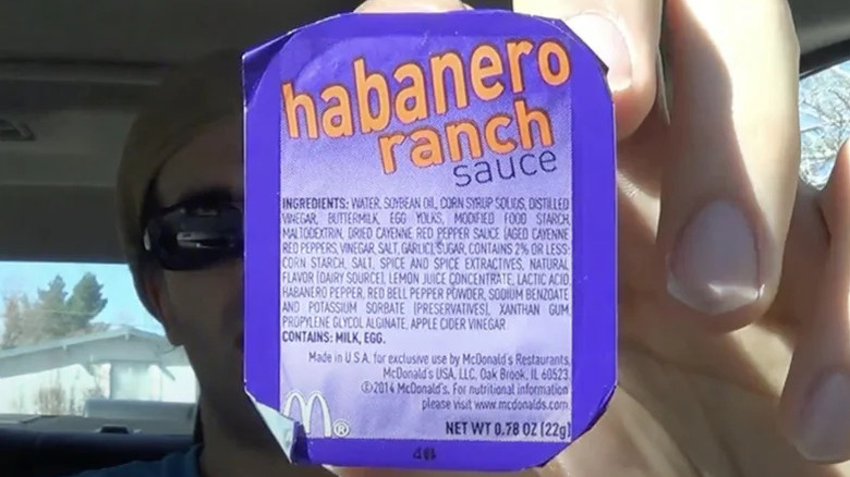 A person holding up a package of McDonald's Habanero Ranch Sauce