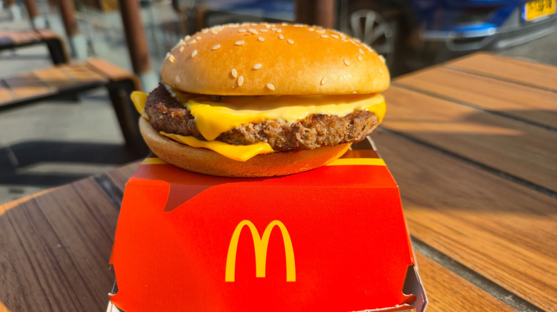 A McDonald's quarter pounder sitting on a red McDonald's takeout box