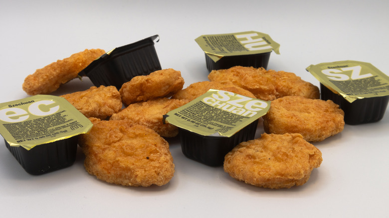 Packets of McDonald's Szechuan Sauce with chicken nuggets on a white background