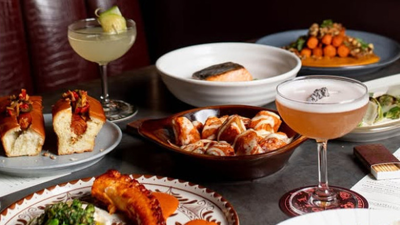 Two cocktails and a spread of brunch dishes on a booth table at Iberian Pig