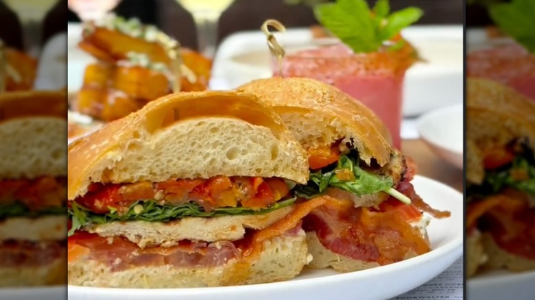 A BLT sandwich and a pink cocktail in the background