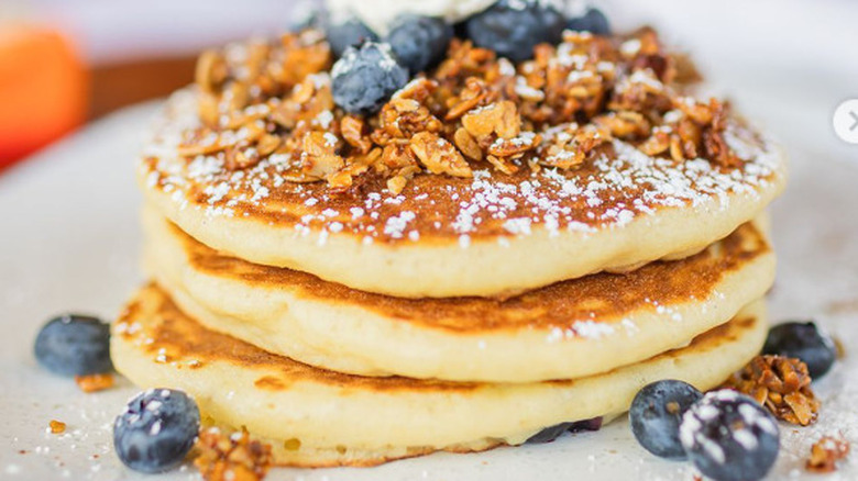 A stack of blueberry pancakes topped with granola