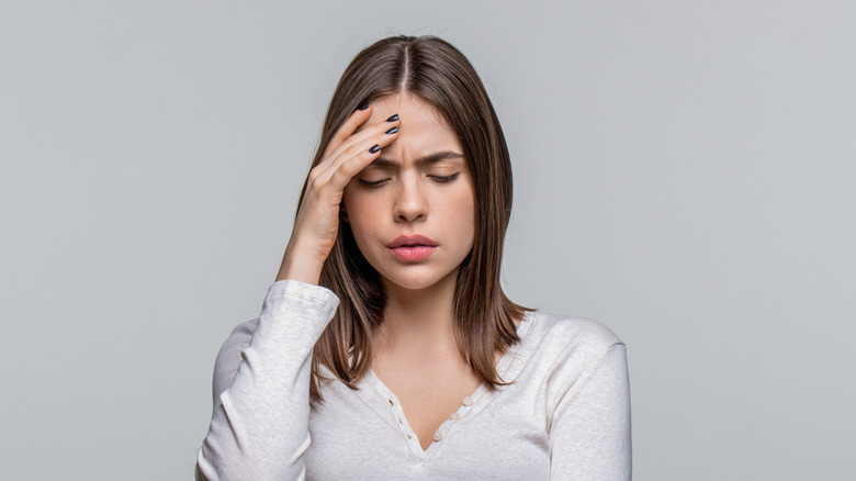 woman holding hand to head feeling stressed