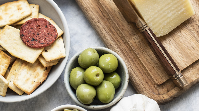 cheese, crackers, olives, and snacks on table