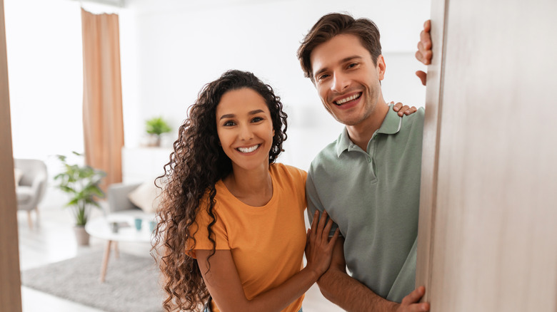 couple smiling behind open door