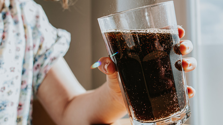 Child holding a glass of dark soda
