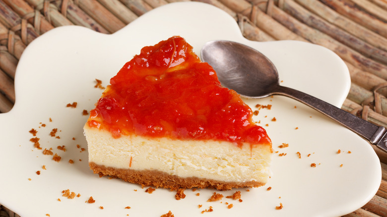 Slice of guava cheesecake on plate with metal spoon