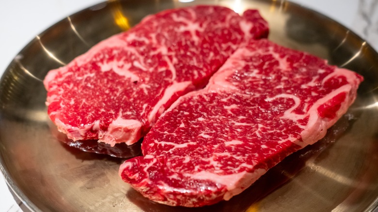 Two raw Hanwoo steaks in a stainless steel skillet