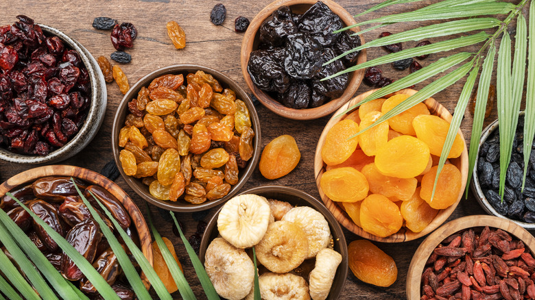 variety of dried fruits in ramekins on a wood surface