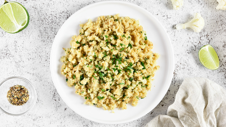 roasted cauliflower rice on a white stone background with limes