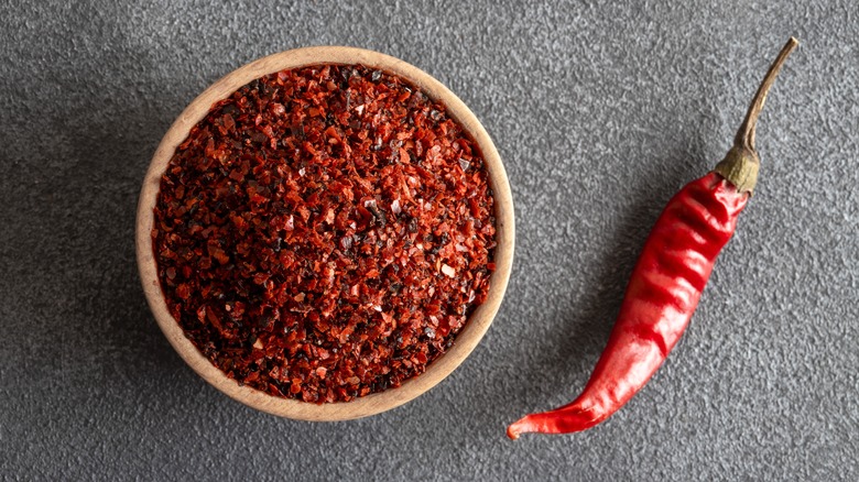 red chili beside a cup of red chili flakes for spice