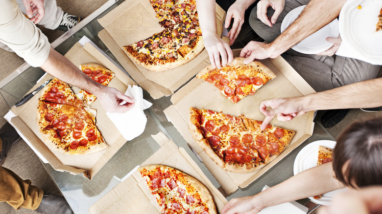 People removing slices of pizza from delivery boxes