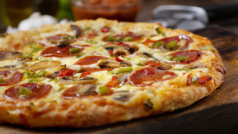 Whole deluxe pizza on cutting board