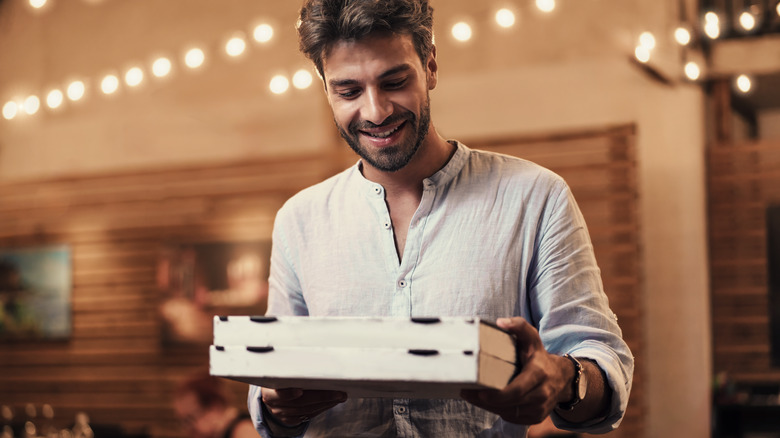 Man picking up to-go pizza order from restaurant