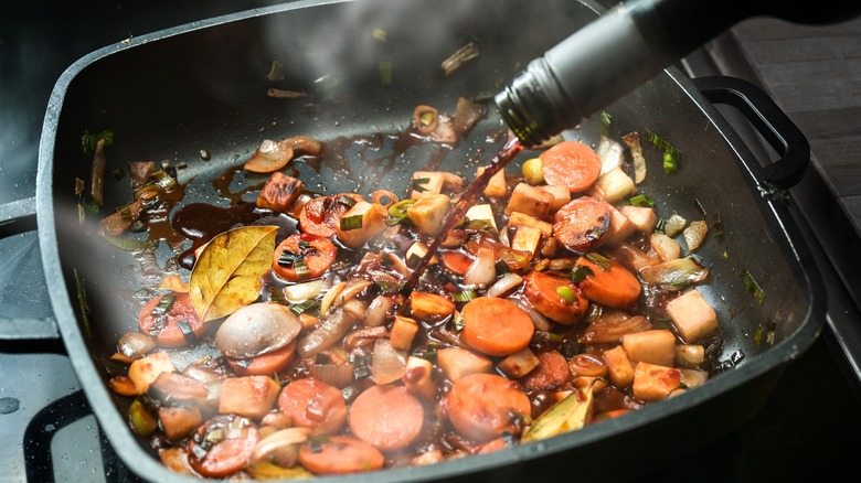 Deglazing a pan of vegetables with wine