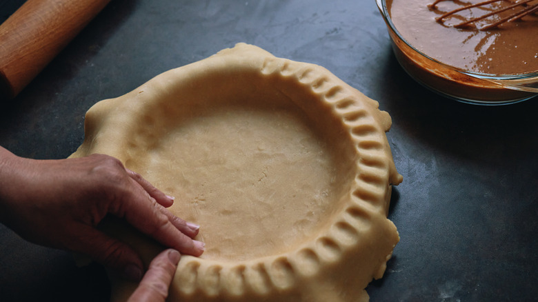 Homemade pie crust being place into a pie dish