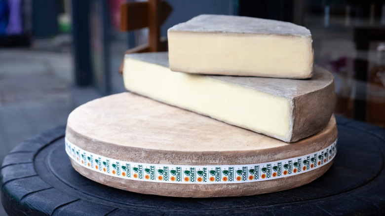 A whole wheel and wedges of Comté cheese