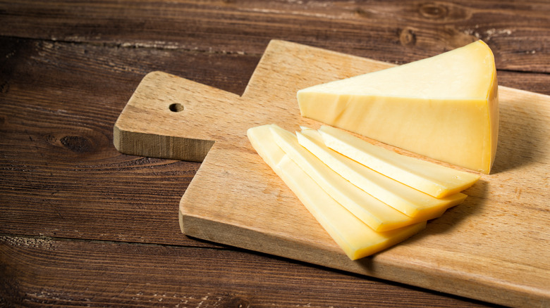 Slices of a hard-aged Italian cheese on a wooden cutting board.