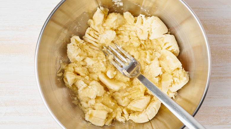 Mashed bananas in a bowl with a fork