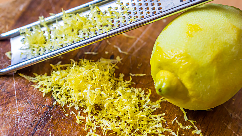 Lemon zest with grater on brown surface