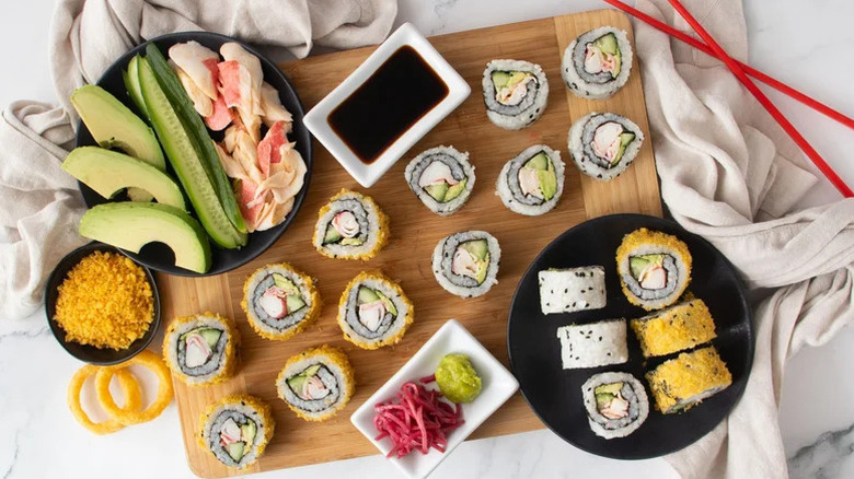 a spread of At-Home California Rolls with soy sauce, wasabi, pickled ginger, and other accompaniments