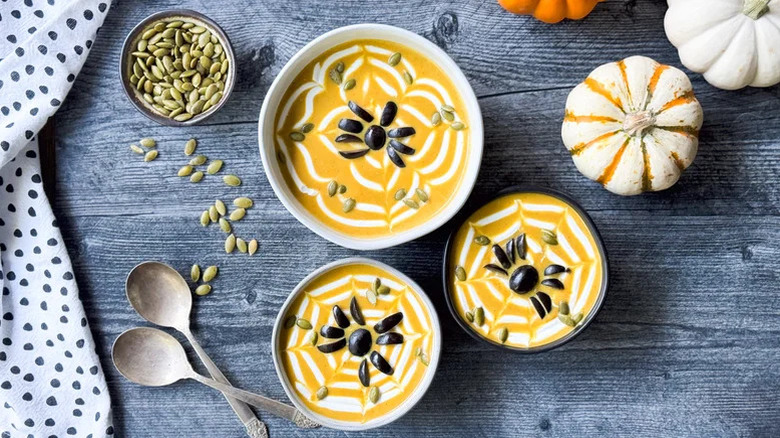 Pumpkin curry soup with toasted pumpkin seeds in the shape of a spider as garnish