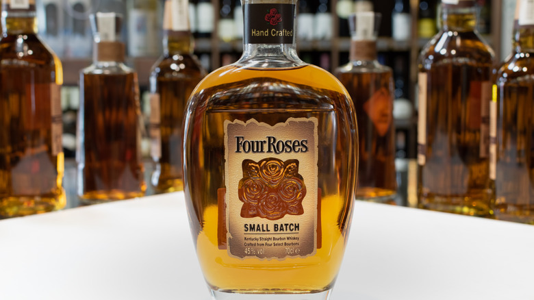 A bottle of Four Roses Small Batch in the foreground of a lineup of bourbon bottles.