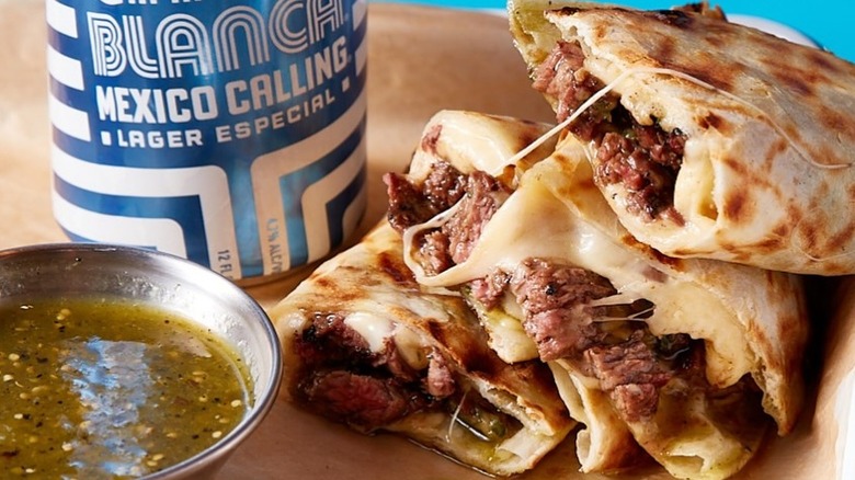 Mexican street quesadillas with a dipping sauce and a can of beer at Cruz Blanca