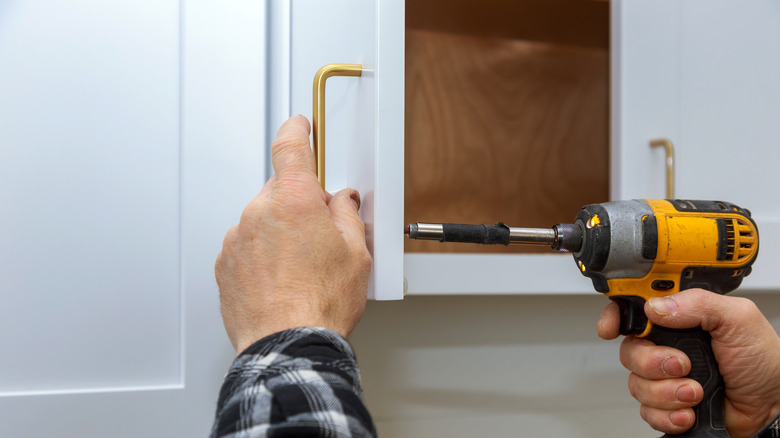 Man installing golden kitchen hardware