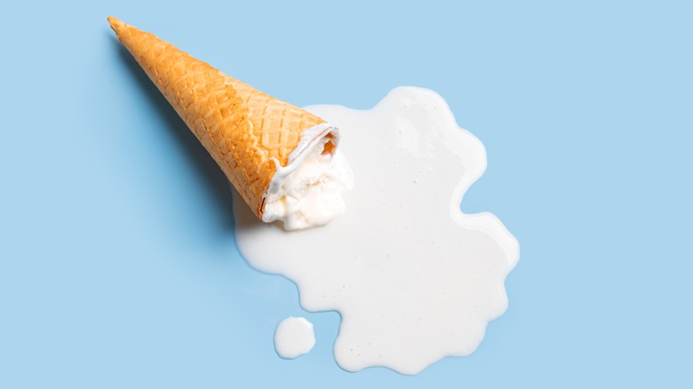 Ice cream cone with melted ice cream on blue background