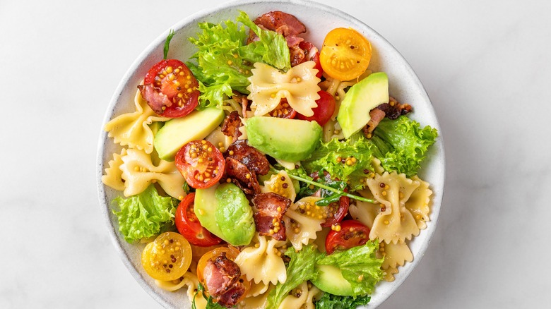 Pasta with large avocado pieces, tomatoes, and lettuce