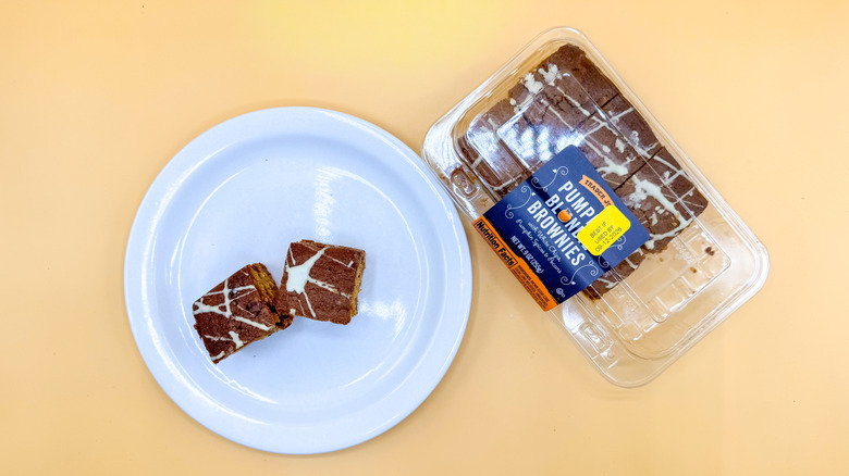 Package of Pumpkin Blondie Brownies with few pieces on a plate beside it