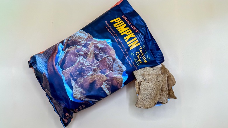 Bag of Pumpkin Tortilla Chips with a few pieces beside it on a yellow surface