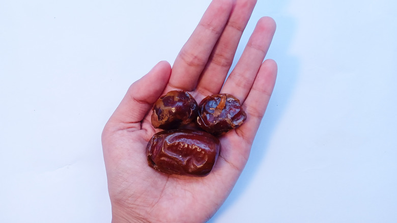 Hand holding three date fruits