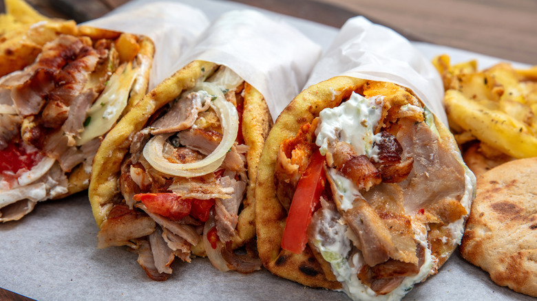 Several gyros with tzatziki, tomates, and onions