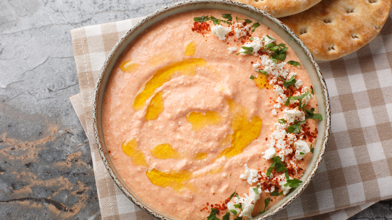A bowl of orange sauce garnishes with olive oil and cheese