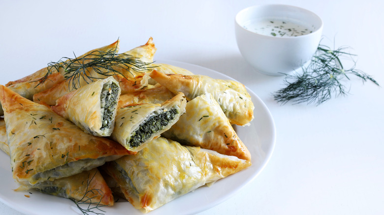 A white plate piled high with spanakopita