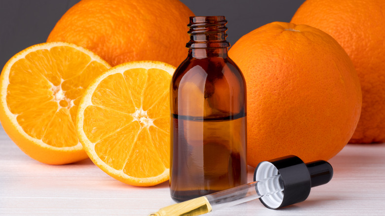 Bottle filled with orange extract with orange slices in background