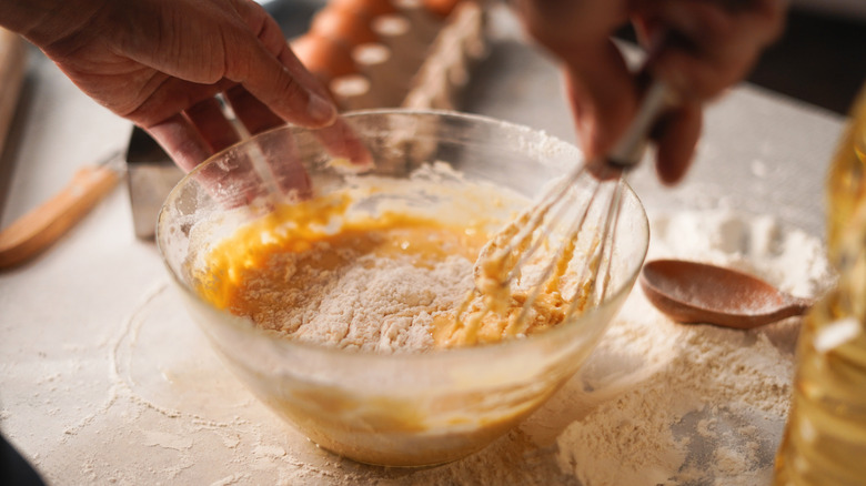 Person mixing cake batter in bowl with whisk