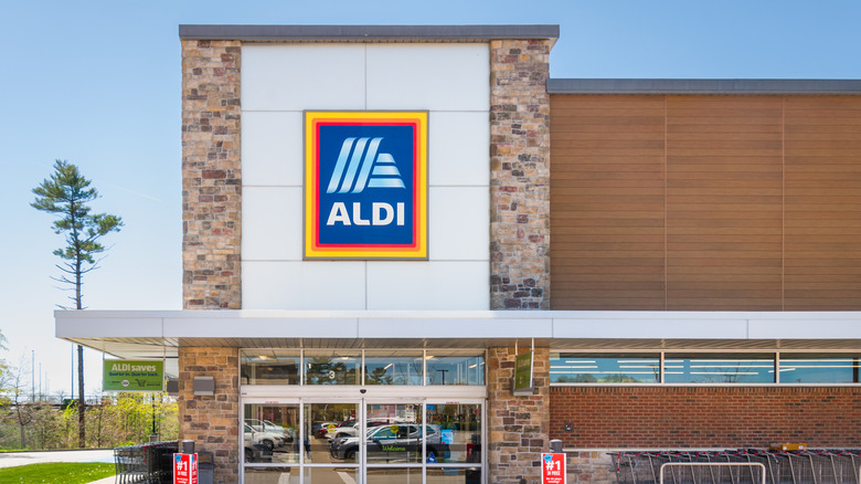 Front of an aldi grocery store with carts lined up on the right of doors.