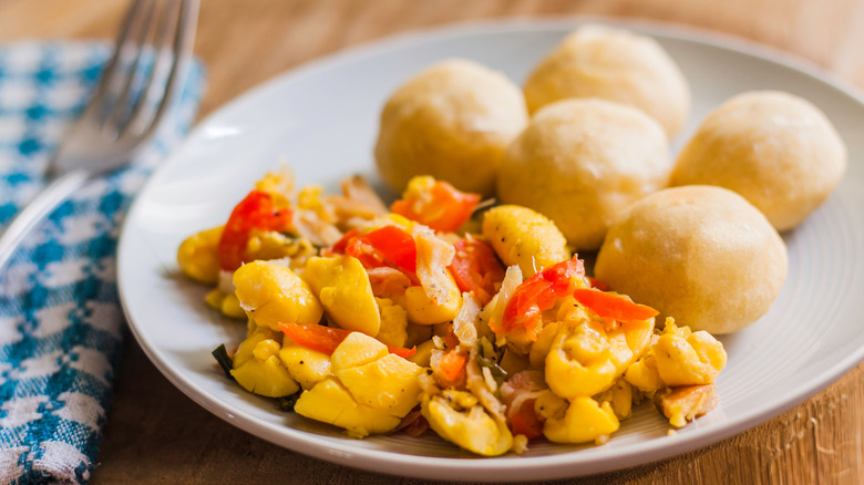 A plate with ackee and salt fish next to dumplings