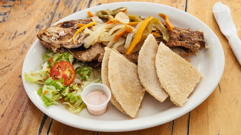 A plate with fried fish, bammy, and a salad