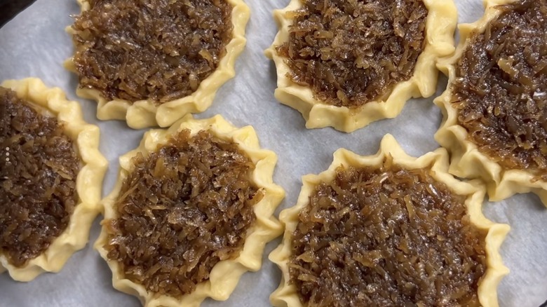 Jamaican Gizzadas lined up on a baking sheet before baking